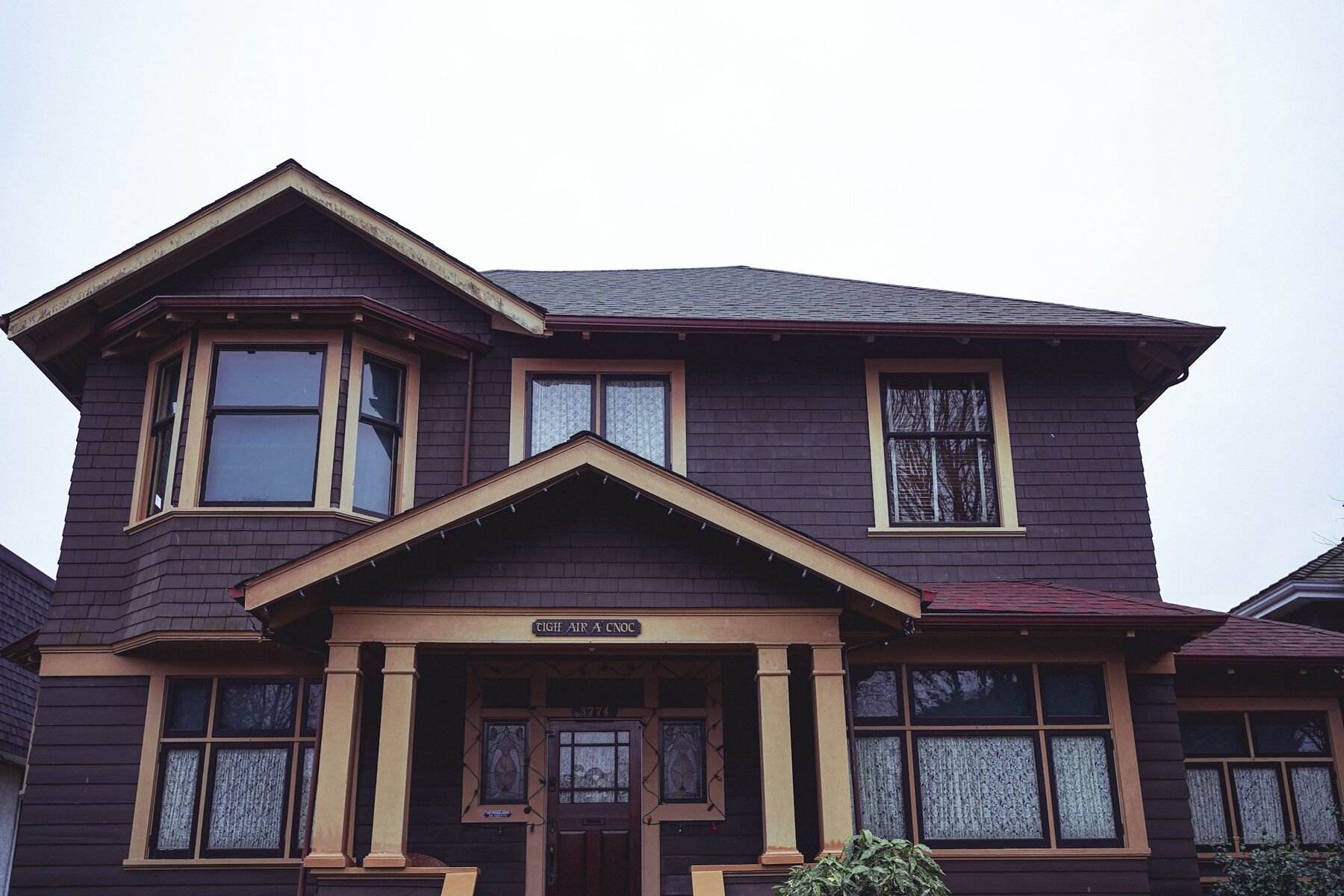 A heritage Edwardian house in Vancouver, dark exterior with carved decorative trim and a covered porch