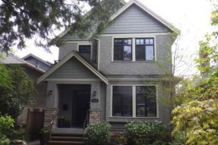 A grey craftsman heritage house with stone foundation