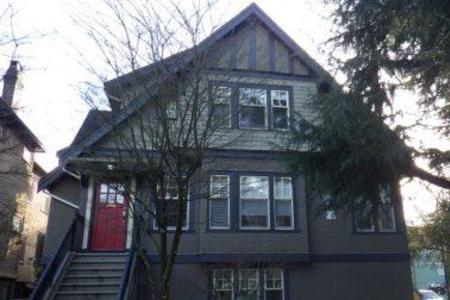 A dark grey heritage house with a red front door